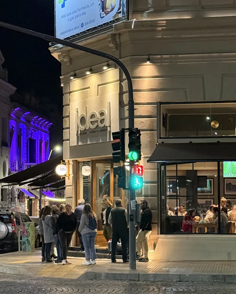 La esquina del Ideal de noche, con gente en la vereda